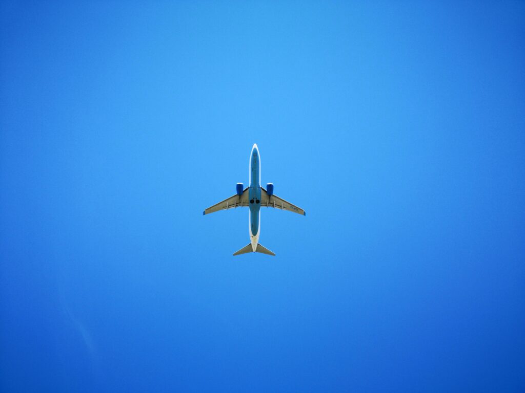 An airplane soaring against a vibrant blue sky, captured from below, representing air travel and freedom.